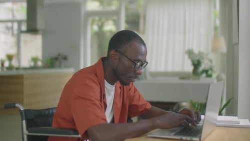 Man in Wheelchair Working on Laptop at Home