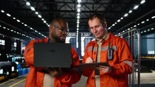 Colleagues Use Laptop and Tablet to Guide Personnel During Fabrication