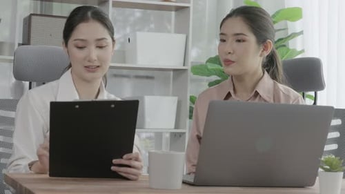 Two young enthusiastic businesswoman working together in the office workspace.