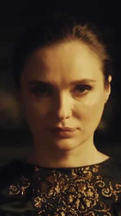 Close-up portrait of a woman with open stern eyes on a dark background