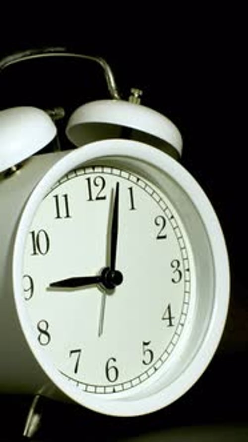 White Alarm Clock Time Lapse on Black Background