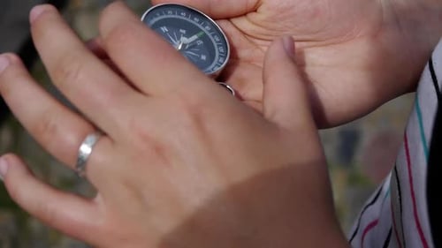 young woman takes out a compass and adjusts it