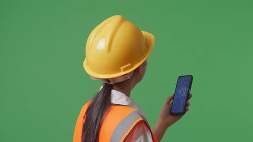 Asian Female Engineer Looking At The Wind Turbine Blueprint On Smartphone In The Green Screen