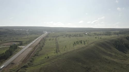 Wide Road Travels Amid Verdant Meadows with Few Scattered Trees