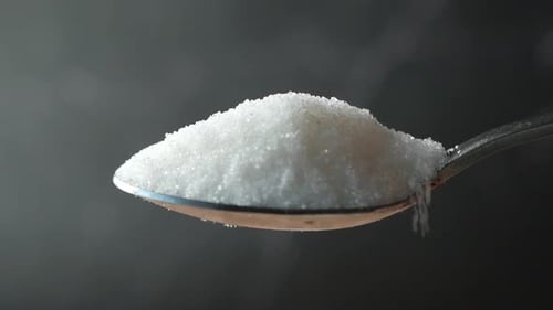 Zeitlupe von weißem Zuckertropfen aus einem Löffel