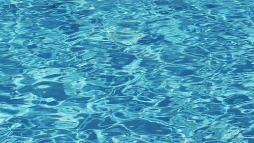Ondulations sur l'eau de la piscine sur une surface claire.