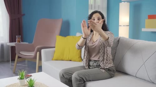 Woman Smiling and Clapping on a Couch Indoors