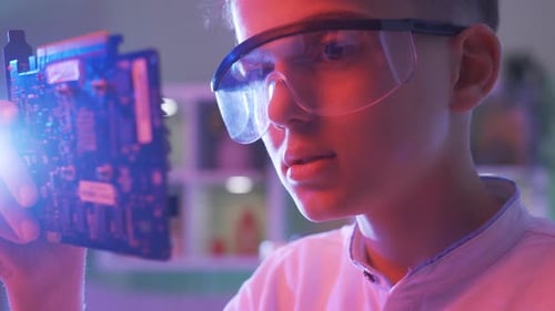 Child Scientist Examines Computer Component in Lab