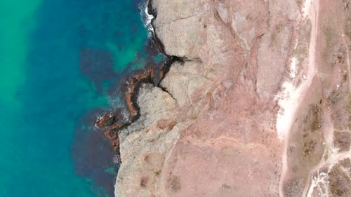 Aerial Top Down View of Rocky Shore and Turquoise Ocean Media