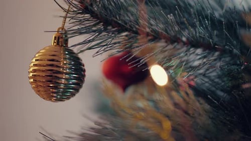 Gold Christmas Balls And Lights Hanging On A Christmas Tree. - close up slider