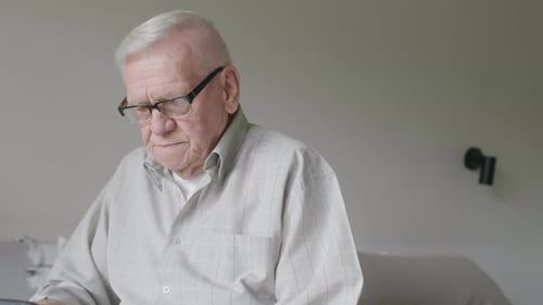 Senior Man Uses Tablet in Brightly Lit Room
