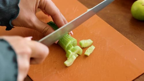 Person schneidet Gurke auf Holzschneidebrett für Rezept