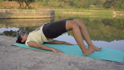 fille amateur faisant une pose de yoga, pose de bridge, Setu Bandha, Sarvangasana, au bord du lac