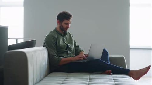 Man is Working with Laptop at Home Remote Online Office of Freelancer Guy is Sitting on Couch
