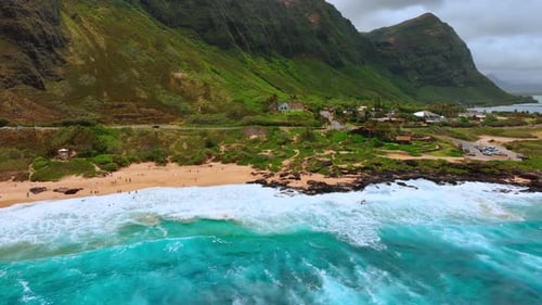 Turquoise water of the Pacific Ocean splashes on the sandy beach.