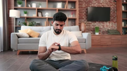 Arabic Man Setting Heartrate Watch During Home Training