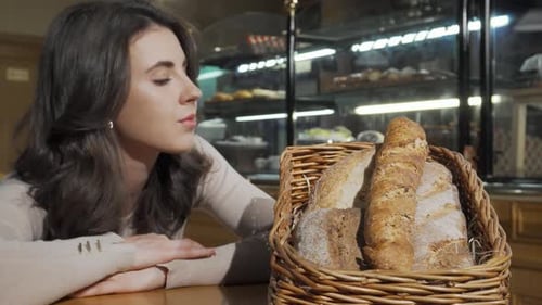 Delighted Woman Savoring the Aroma of Freshly Baked Bread in a Cozy Bakery