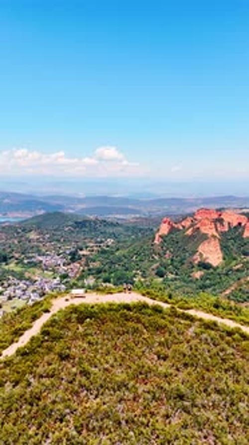 A couple of tourists stand on the mountain top sightseeing the splendid panorama