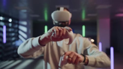 Man Using VR Headset and Controllers to Explore the Metaverse in a Neon Room