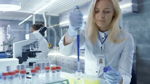 Female Medical Reasercher Works with Micropipette. She Tests Analysis. Scientists are Working in th