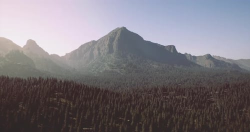 Majestic Mountain Peak Rises Above Lush Forest Under Clear Blue Sky