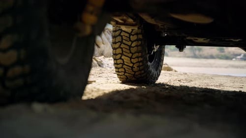 A tire of a car parked on a beach.
