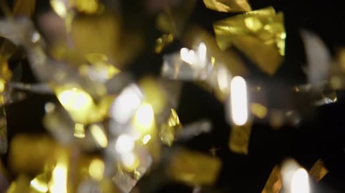 Gold and Silver Confetti Falling on Black Background