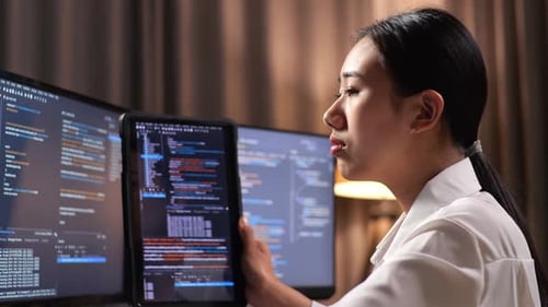 Asiatische Programmiererin schaut sich die Datenbank auf dem Tablet an, während sie eine App für die Entwicklung einer Software-Ingenieurin erstellt