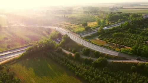 Aerial Drone Footage: Long Haul Semi Trucks Driving on the Busy Highway in the Rural Region of Ital