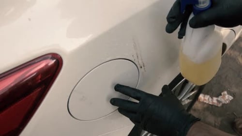 Close up of a male wearing a black gloves removing car stains