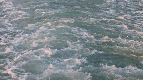 Nahaufnahme von Meereswellen, die sich mit dynamischer Bewegung hinter dem Heck des Schiffes bewegen und schäumen