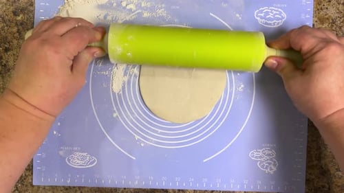 Rolling out round pieces of raw dough with a rolling pin to make patties. Top view.