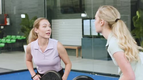 El equipo de entrenamiento femenino discute la táctica antes de practicar el swing de derecha y el servicio en la cancha de pádel