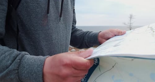 Hiker Navigates Using Paper Map on Coast