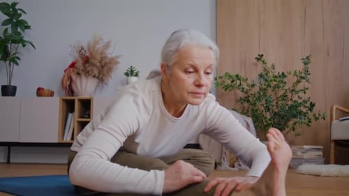 Senior Woman Doing Forward Bend Yoga Stretch at Home