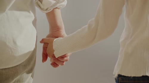 Child and Adult Holding Hands Closely Indoors