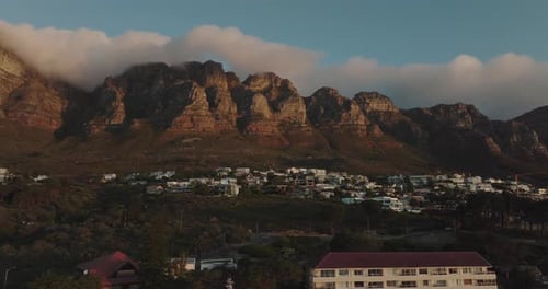 Drone flies slowly sideways over Camps Bay in Cape Town South Africa - Building on the hillside view