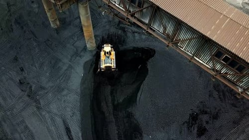Bulldozer sorts coal. Extractive industry, anthracite. Coal industry. Aerial view.