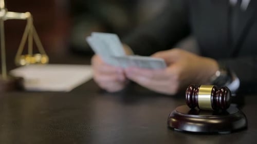 Nahaufnahme von Hammer im Gerichtssaal mit Handzählung von Geld im Hintergrund