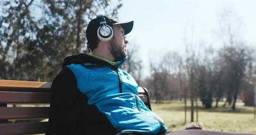 During Run Man Tiredly Sits Down on Bench and Checks the Distance He Has Run on Watch