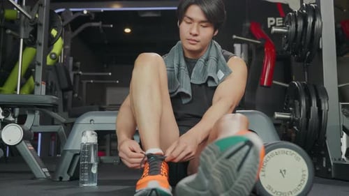 Person's Hand Tying a Shoelace on Gym Floor Highlighting the Importance of Proper Preparation for