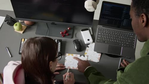 Two Young Colleagues Collaborating on a Coding Project in an Office