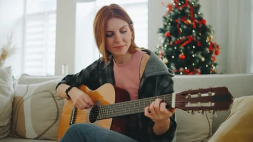 Woman Playing Guitar Indoors at Christmas Time