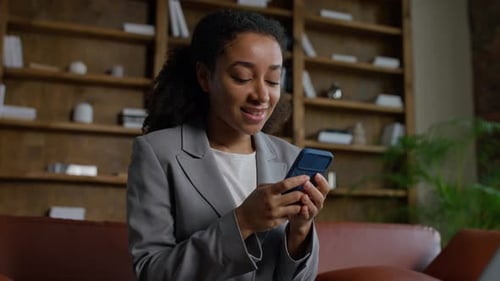 Woman Using Phone Smiling at Home on Couch
