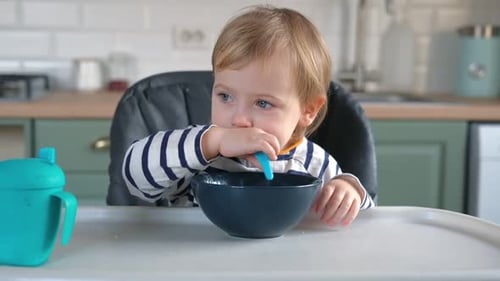Child Eating Cereal at Kitchen Table