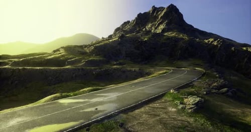 Winding Road Leads to a Majestic Mountain Under a Bright Sky at Sunset