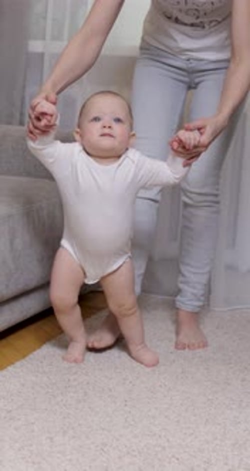 Happy Little Baby Girl Learning to Walk with Mother Help