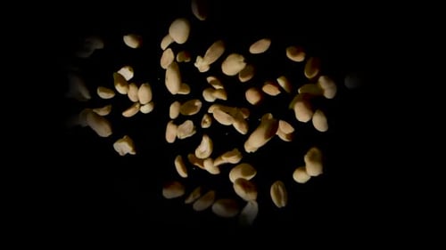 Peeled Peanuts Falling on Black Background