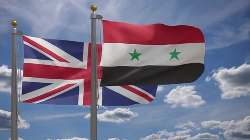 United Kingdom and Syria Flags Waving on Poles Against Blue Sky
