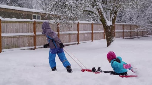 Kids enjoying winter fun sledding downhill in deep snow